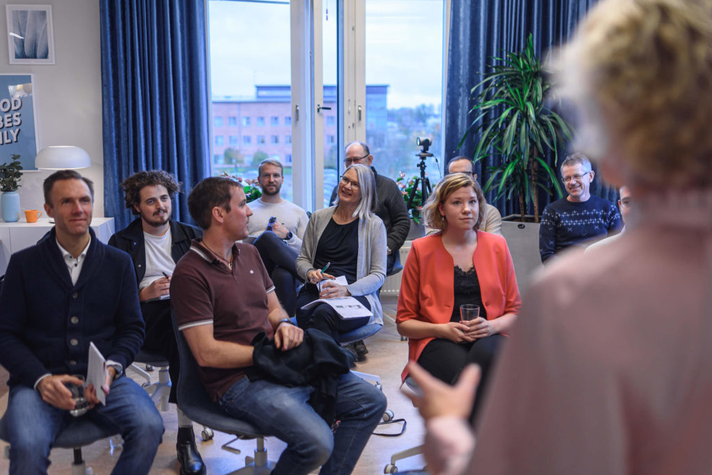 Ryggen på en kvinna som står framför personer och föreläser